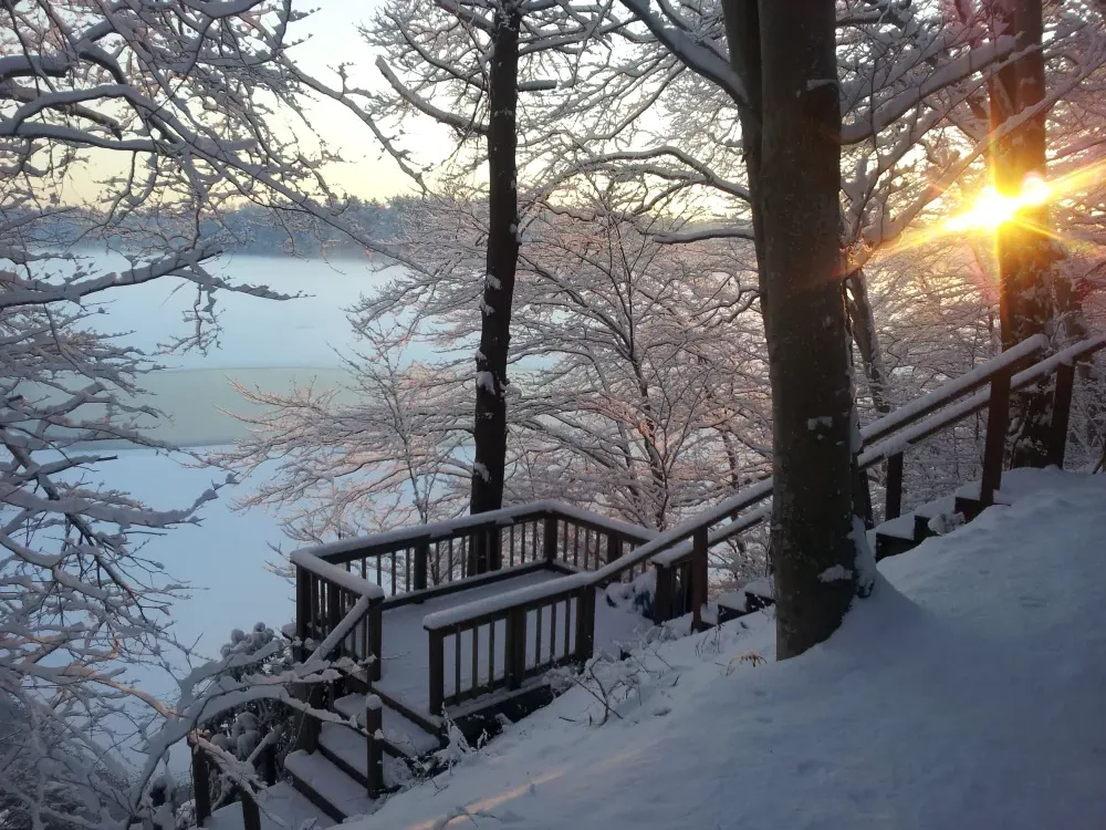 Wooden deck and stairs above a lake in snow